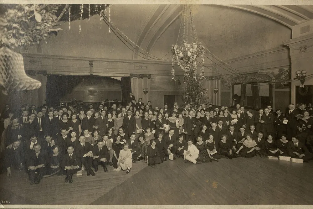A large group of Buzza Company employees posed in a decorated hall at their 1922 Christmas party
