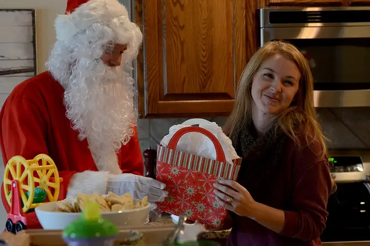 A woman smiling as she receives a Christmas gift basket from Santa