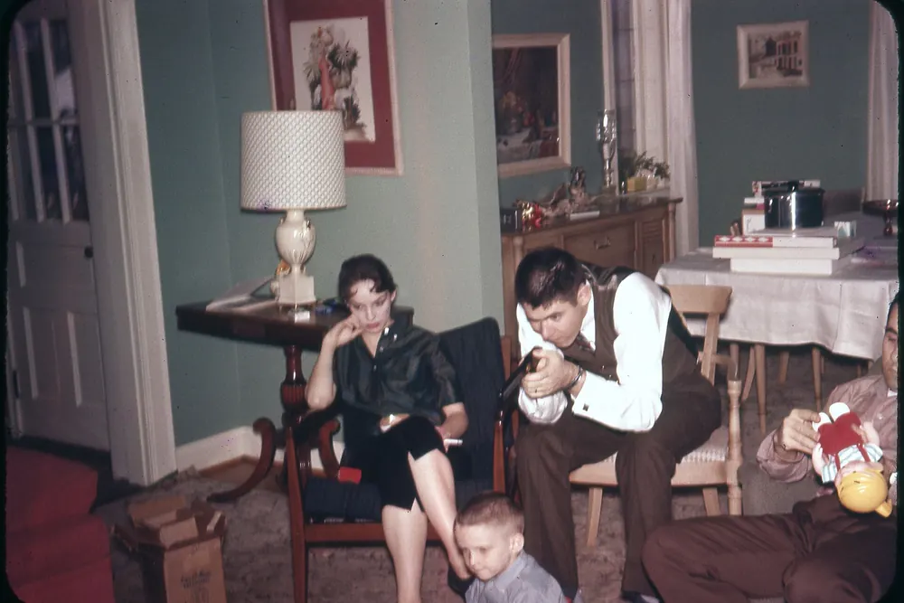 Two adults and a child with Christmas gifts in a living room